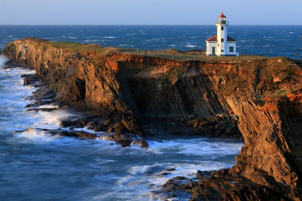 Beautiful view of the lighthouse, waves crashing on the rocky shore