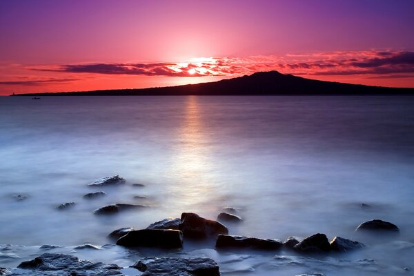 Amanecer en nueva Zelanda. Piedras en el agua