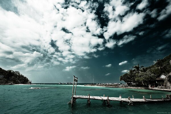 Brücke am Strand am Meer unter dem Himmel in den Wolken