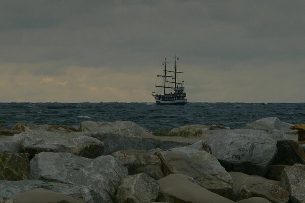 Un barco a lo lejos. Grandes piedras en la orilla del mar