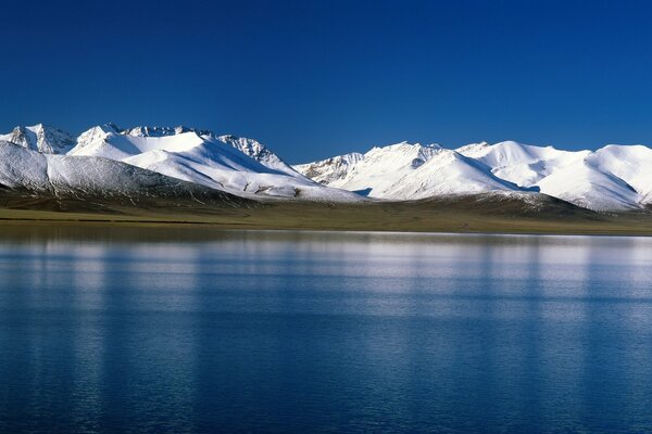 Lago azul en el fondo de las montañas cubiertas de nieve