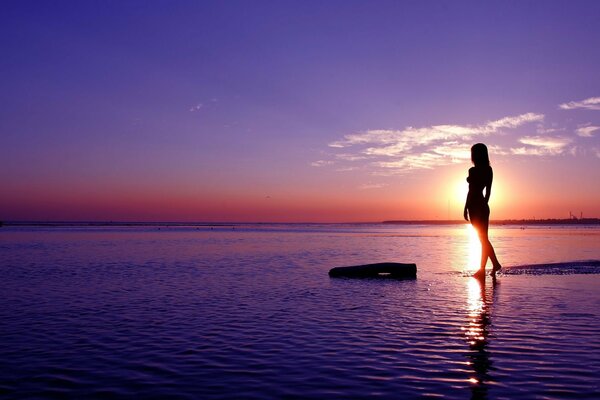 Photo of a girl in the sea against the sunset