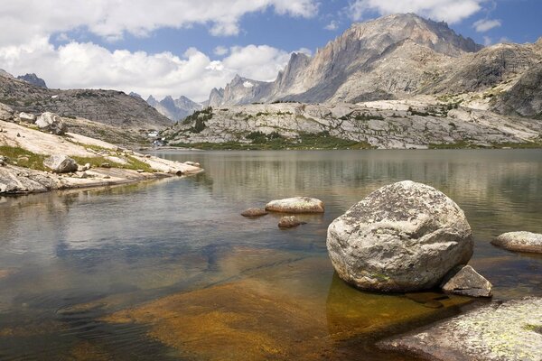 Pierres sur la rivière de montagne sur fond de ciel nuageux et montagnes