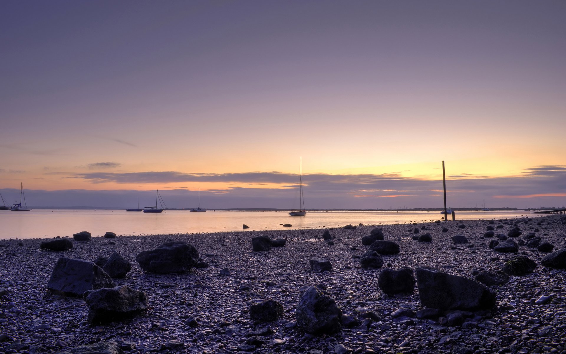 beach boat ocean stones sky sunset water