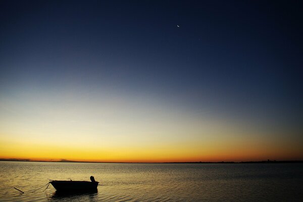 Barco solitario en el mar, en el fondo del cielo al atardecer