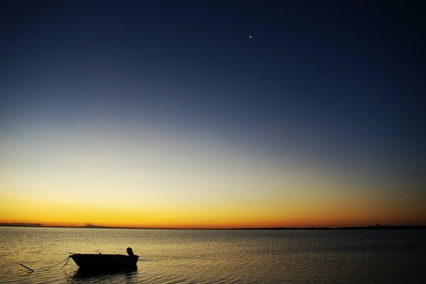 Bateau solitaire dans la mer, sur fond de ciel coucher de soleil