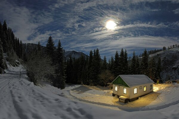 Winterhaus unter dem Mond im Wald