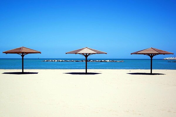 Sombrillas de playa junto al mar en arena blanca