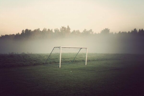 Campo deportivo con portería de fútbol en la niebla