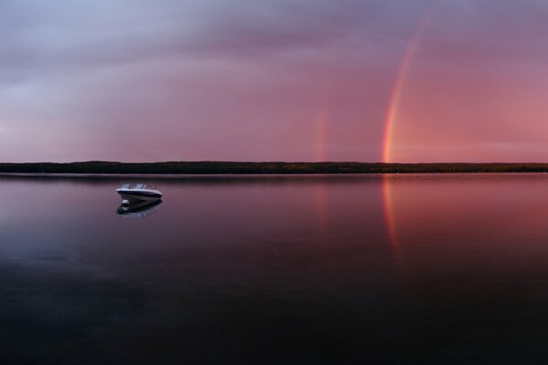 Noche rosa con un arco iris en el lago