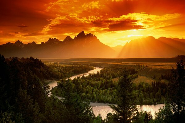 Brillante puesta de sol sobre el río en el valle. Montañas en el horizonte