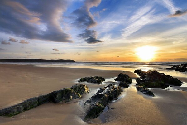 Sunset over the sea. sandy beach. rocks. the sun