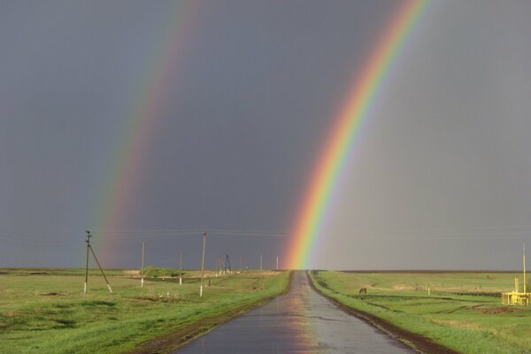 Double rainbow. A road in the middle of meadows