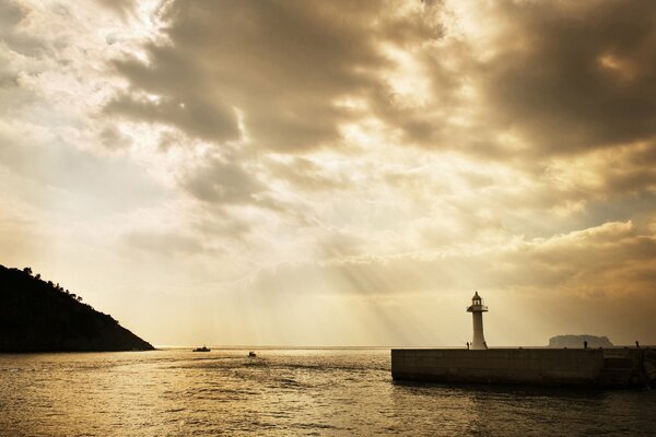 Lighthouse on the pier in the light of the morning rays of light