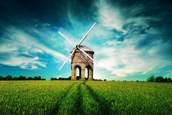 A mill with white wings on a green field