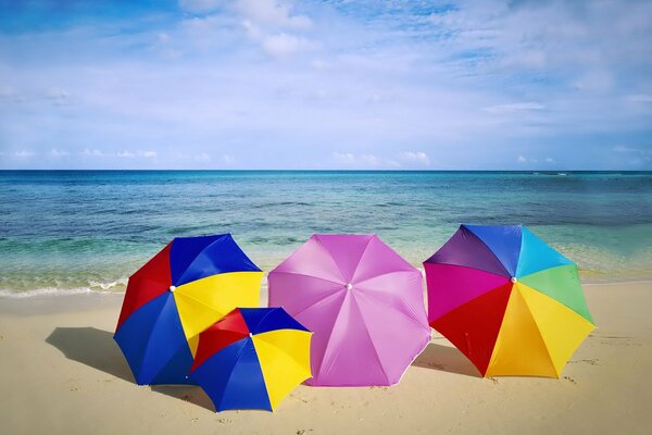 Colorful umbrellas on the beach against the background of the blue sea