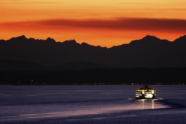 Ferry nocturno en medio de una puesta de sol naranja