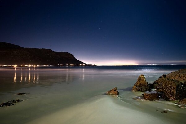 Côte rocheuse de nuit avec les lumières de la ville à l horizon