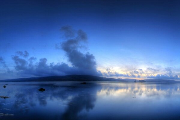 Der See spiegelt weiß-blaue Wolken im Wasser wider