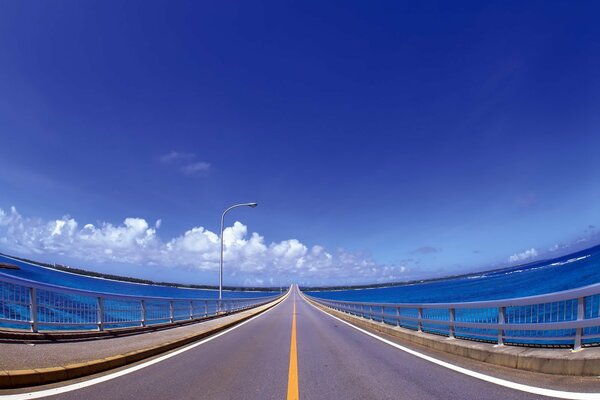 A flat road with a yellow marking line against a background of white clouds