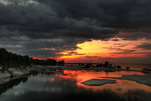 Misteriosa puesta de sol cerca del agua antes de la tormenta