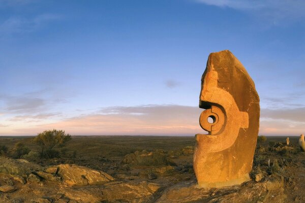 Misteriosa scultura in pietra sullo sfondo di una pianura verde