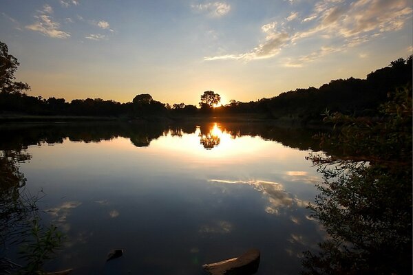 Le coucher de soleil illumine le lac et autour des arbres