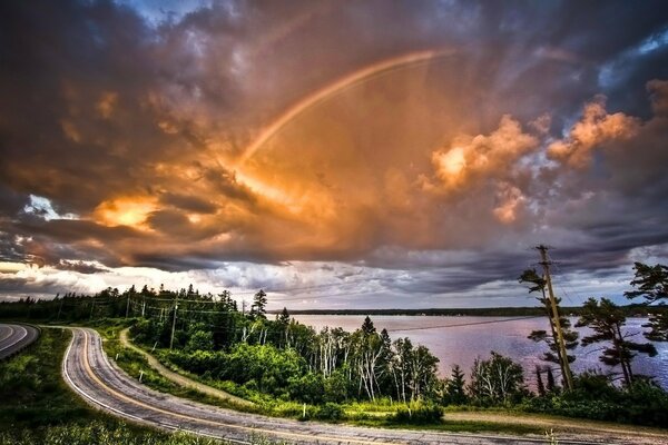 Winding road on the background of clouds and rainbows