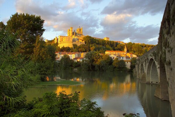 View of the Church of St. Nazarius in France from the side of the river and bridge