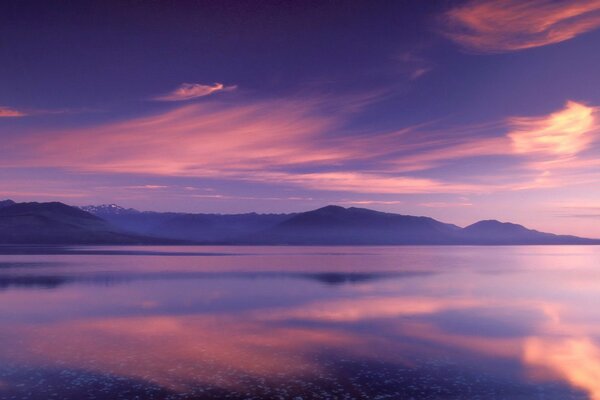 Pink clouds are reflected in a mountain lake