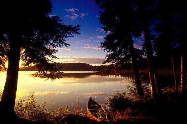 Boat on the lake in the trees and a beautiful sunset