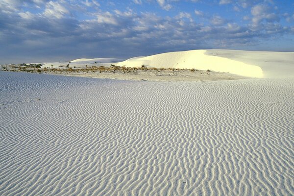 Arena blanca del desierto en un cielo azul gris nublado