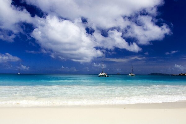 Costa de arena, agua de mar azul y cielo azul