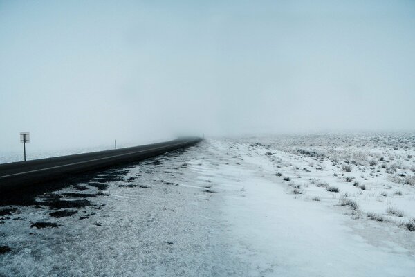 Camino de invierno a través de la niebla