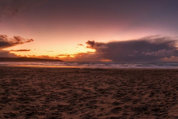 Sandy beach with sunset and clouds