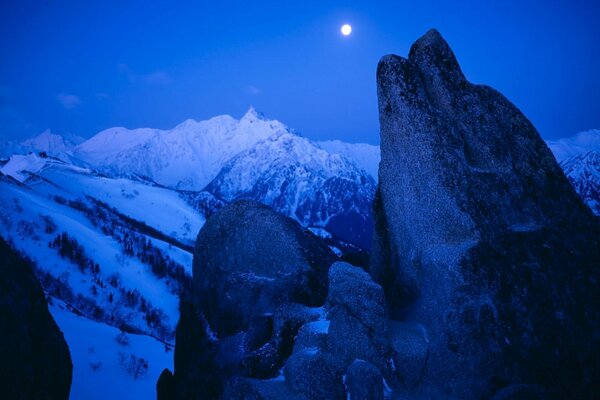 Night landscape of snow-capped mountain peaks in the light of the moon