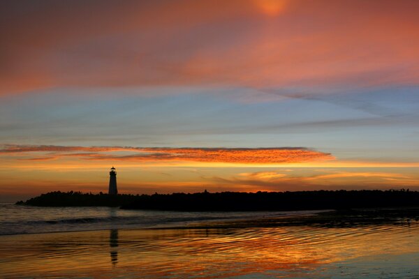 Riflessione del faro e del tramonto nel lago