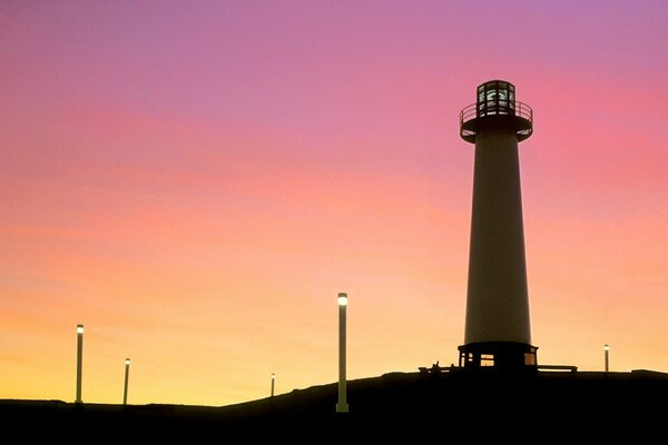 Brennende Laternen und ein Leuchtturm bei Sonnenuntergang