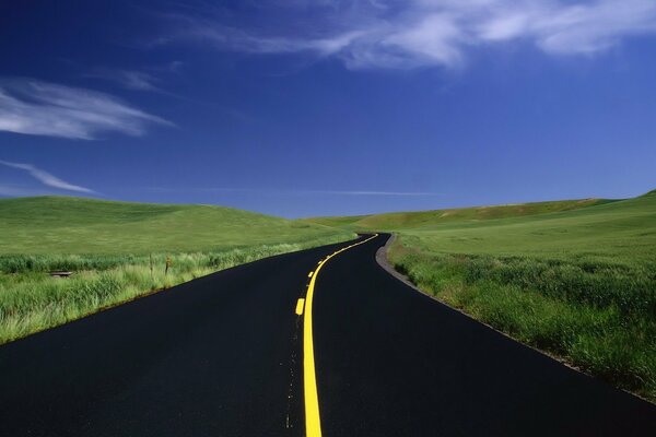 Marcas de carreteras de color amarillo brillante contra campos verdes y cielos azules brillantes