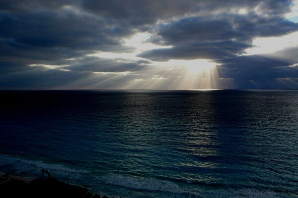 Zachód słońca nad morzem. Słońce przedziera się przez chmury
