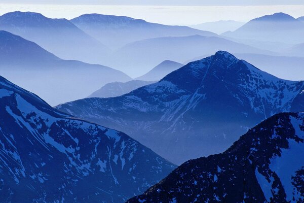 Magische schneebedeckte Berge im blauen Nebel