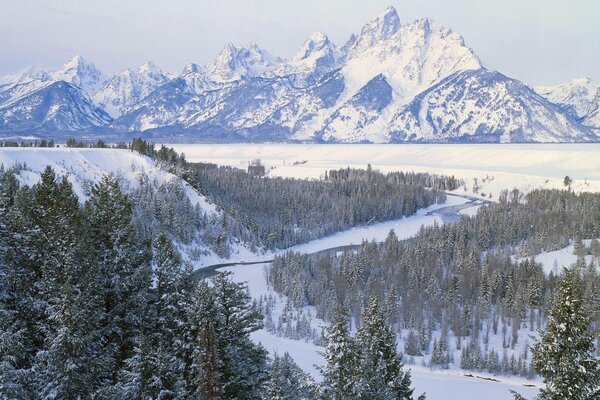 Schneebedeckte Berge und Bäume am Fluss