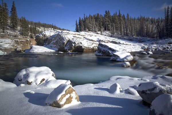 Lago de invierno. Árboles en las montañas