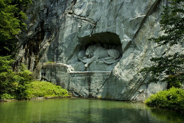 Escultura de un León en una roca contra un fondo de vegetación