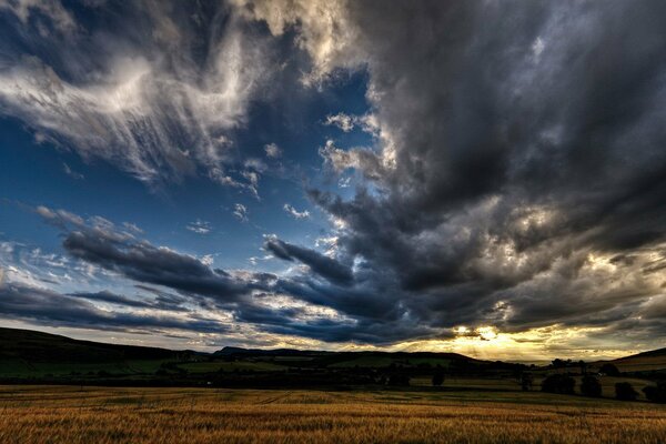 Sonnenaufgang über dem Feld und schwere Wolken