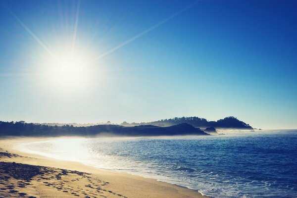 Sol brillante y mar cálido, costa de arena con huellas