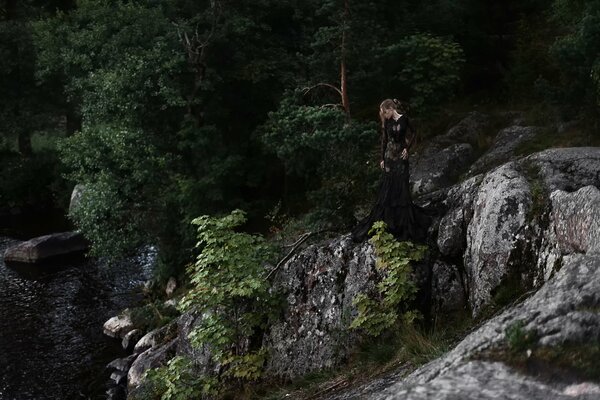 Chica en las piedras contra los árboles