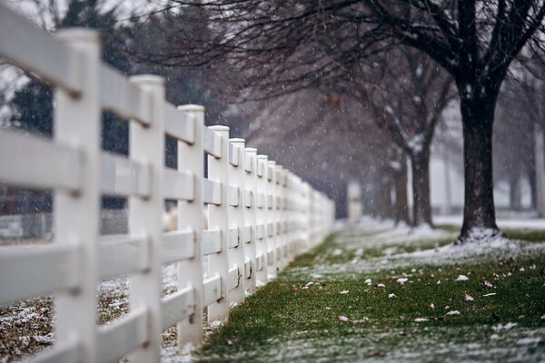 Rue de la ville avec clôture blanche et première neige
