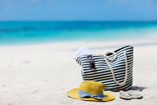 Bag and hat on the sandy shore of the blue sea