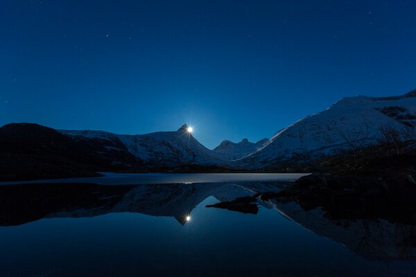 Winter night landscape of a mountain snow-covered lake